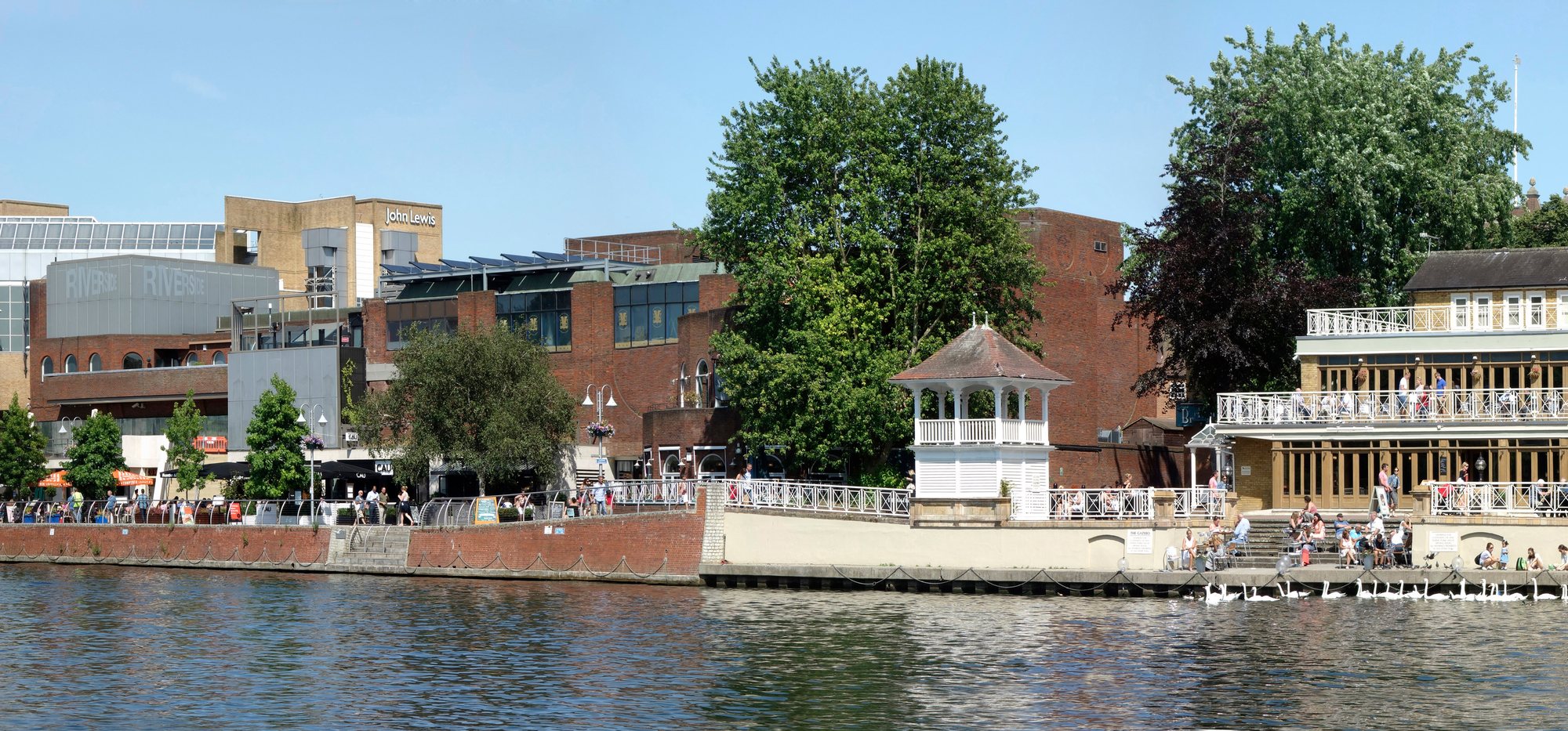 The riverside terraces at Kingston upon Thames — bars and restaurants with parasols facing the Thames, the bandstand, and the John Lewis and Riverside buildings behind